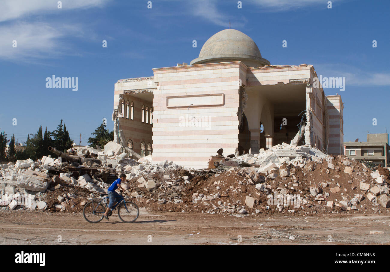 Azaz, Siria. Il 17 ottobre 2012. Un ragazzo corse una bicicletta passato un serbatoio distrutto nei pressi di una moschea danneggiato in un'zaz, Siria il 17 ottobre 2012. Credito: PixelPro / Alamy Live News Foto Stock