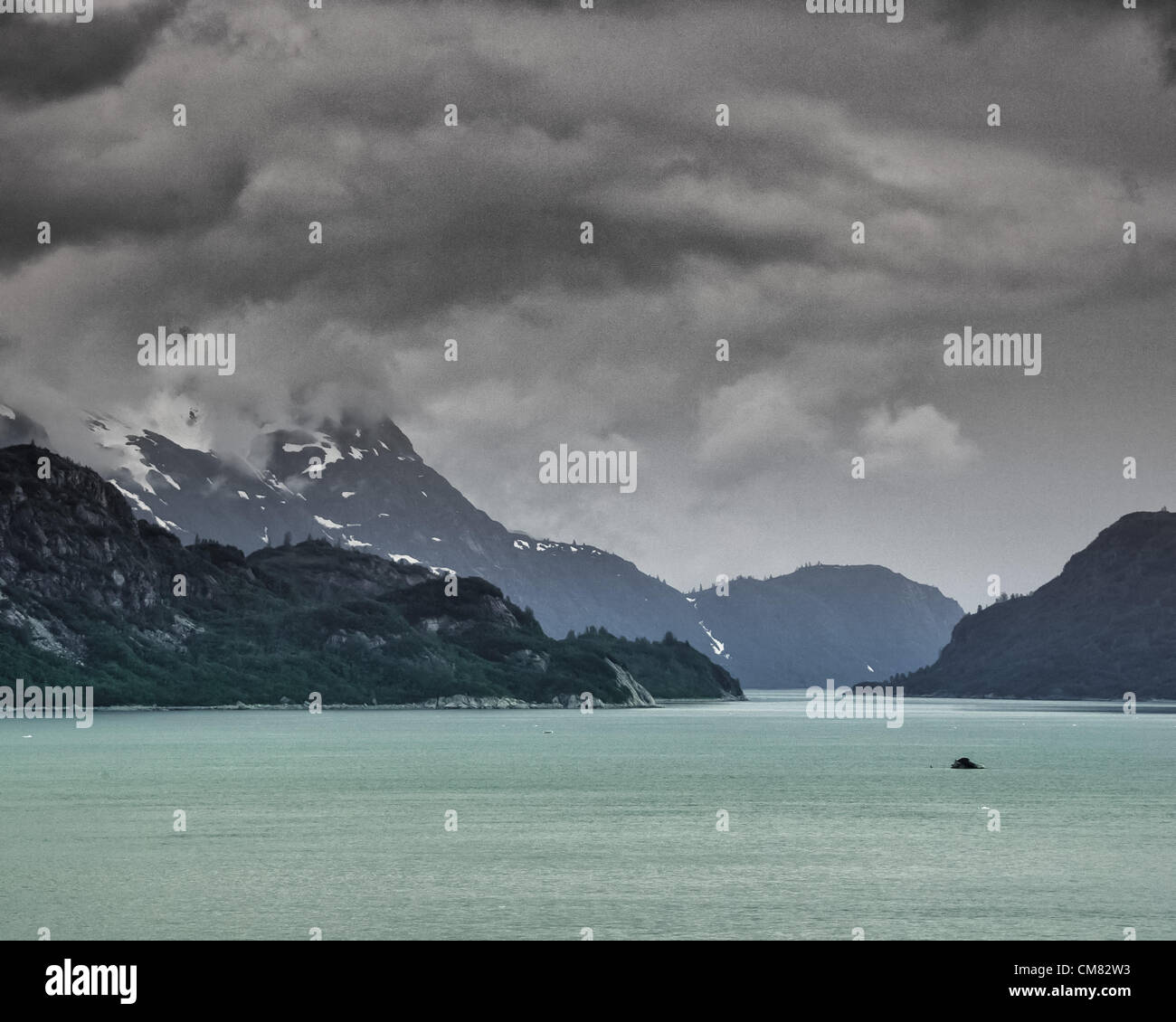 3 luglio 2012 - Glacier Bay, Alaska, USA - lungo le coste del Glacier Bay e il suo aqua acqua colorata, drammatica delle formazioni di nubi, telo le aspre montagne del Fairweather Range. Visitato da quasi mezzo milione di turisti ogni anno, per la maggior parte la nave di crociera passeggeri, Glacier Bay copre 3.3 milioni di acri (1,3 milioni di ettari) di aspre montagne e ghiacciai dinamico, foreste pluviali temperate, coste selvagge, profondi fiordi riparate e fauna selvatica. Un highlight dell'Alaskan passaggio interno e parte di 25 milioni di acri (10,1 milioni di ettari) Sito del Patrimonio Mondiale, è la più grande dell'UNESCO biosph protetto Foto Stock