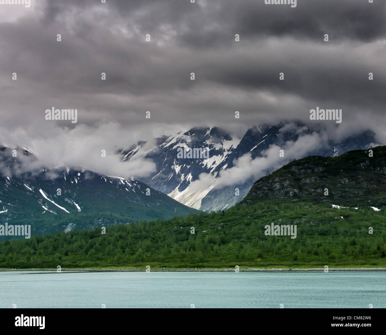 3 luglio 2012 - Glacier Bay, Alaska, USA - lungo le coste del Glacier Bay e il suo aqua acqua colorata, drammatica delle formazioni di nubi, telo le aspre montagne del Fairweather Range. Visitato da quasi mezzo milione di turisti ogni anno, per la maggior parte la nave di crociera passeggeri, Glacier Bay copre 3.3 milioni di acri (1,3 milioni di ettari) di aspre montagne e ghiacciai dinamico, foreste pluviali temperate, coste selvagge, profondi fiordi riparate e fauna selvatica. Un highlight dell'Alaskan passaggio interno e parte di 25 milioni di acri (10,1 milioni di ettari) Sito del Patrimonio Mondiale, è la più grande dell'UNESCO biosph protetto Foto Stock