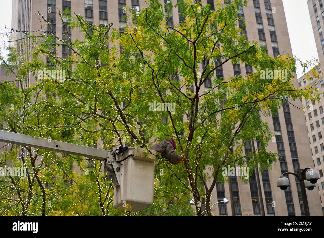 Ottobre 28, 2012, New York, NY; Workman rimuove luci delle vacanze da albero su West 50th Street davanti a uragano di sabbia. Le luci sono stati messi in soli quattro giorni prima. Foto Stock