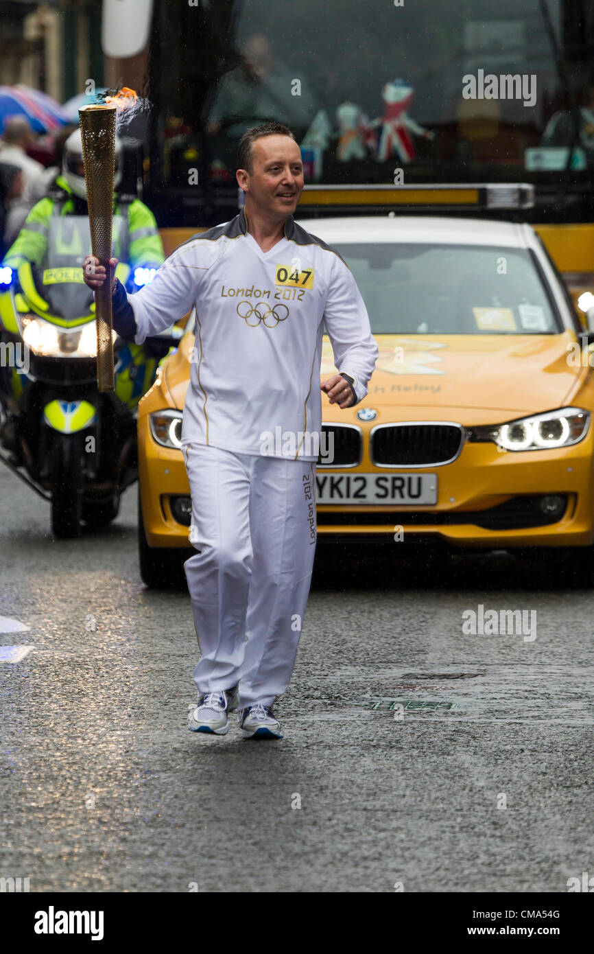 Northampton UK. 2 luglio 2012. Andy Wightman porta la torcia olimpica verso il basso St Giles Street di fronte al Guildhall centro di Northampton, proprio come la pioggia inizia a. Foto Stock