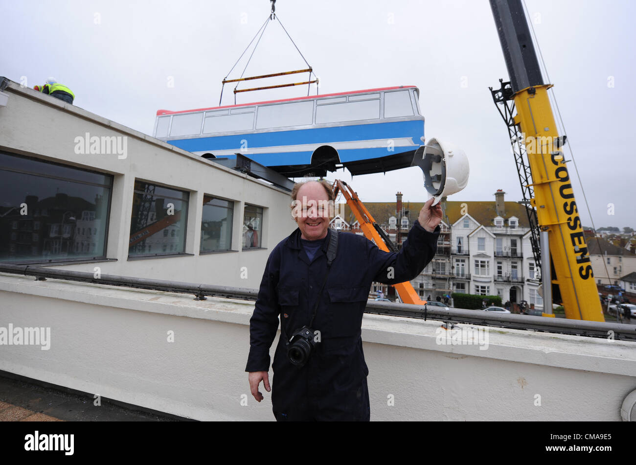 Bexhill, UK. 3 Luglio 2012 - artista Richard Wilson è soddisfatto dopo il suo allenatore è riuscito issato sul tetto del De La Warr Pavilion Bexhill oggi come parte dell'artista Richard Wilson di installazione del chiamato 'appendere su un minuto Lads ho un' idea per il pezzo che è sostenuta da Eddie Izzard ricrea la famosa scena finale del film The Italian Job e saranno in vigore fino al mese di ottobre. Foto Stock