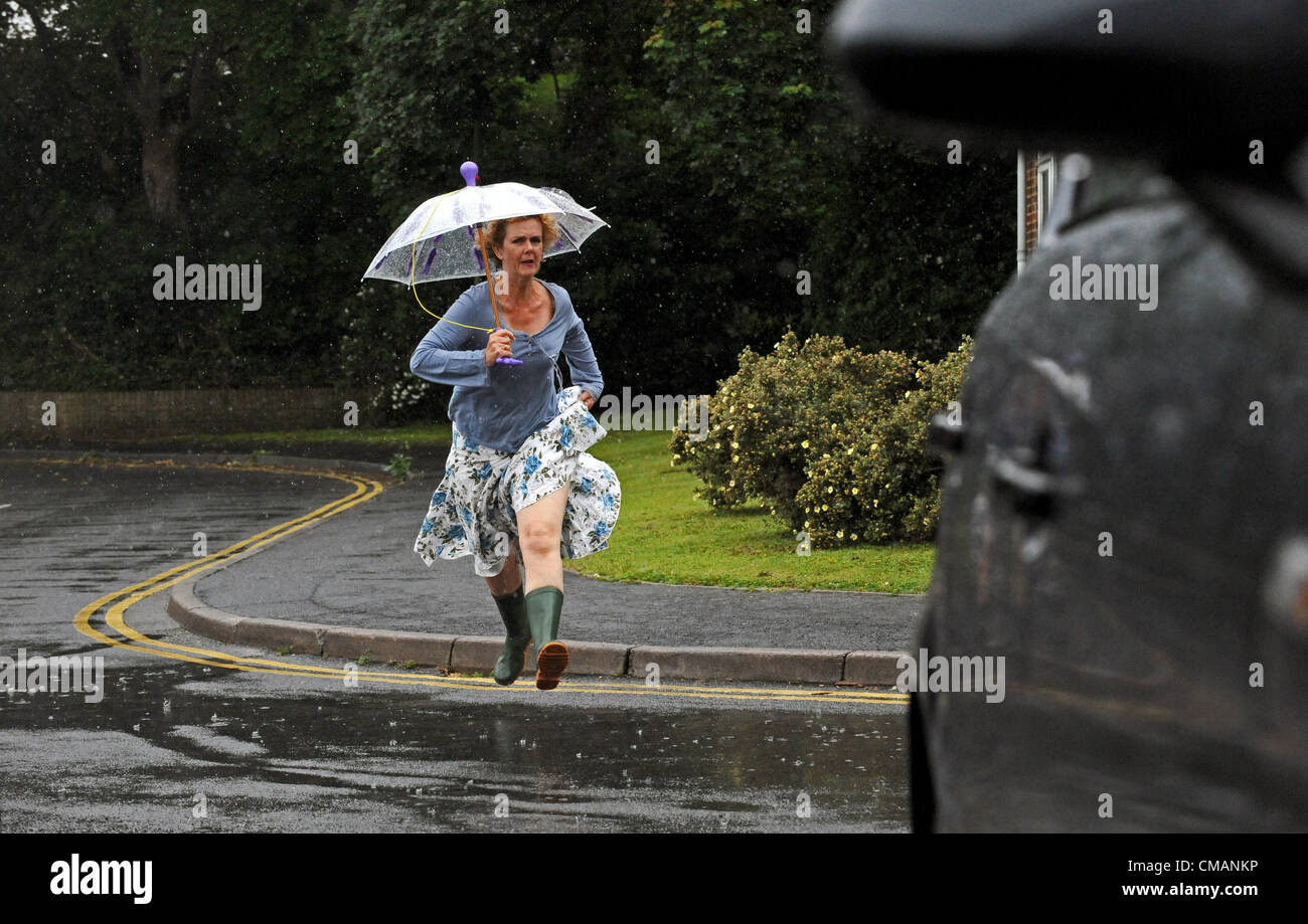 Brighton Regno Unito 6 Luglio 2012 - Una donna rende un trattino per it con un ombrello come lei corre attraverso heavy rain in Brighton questa mattina Foto Stock