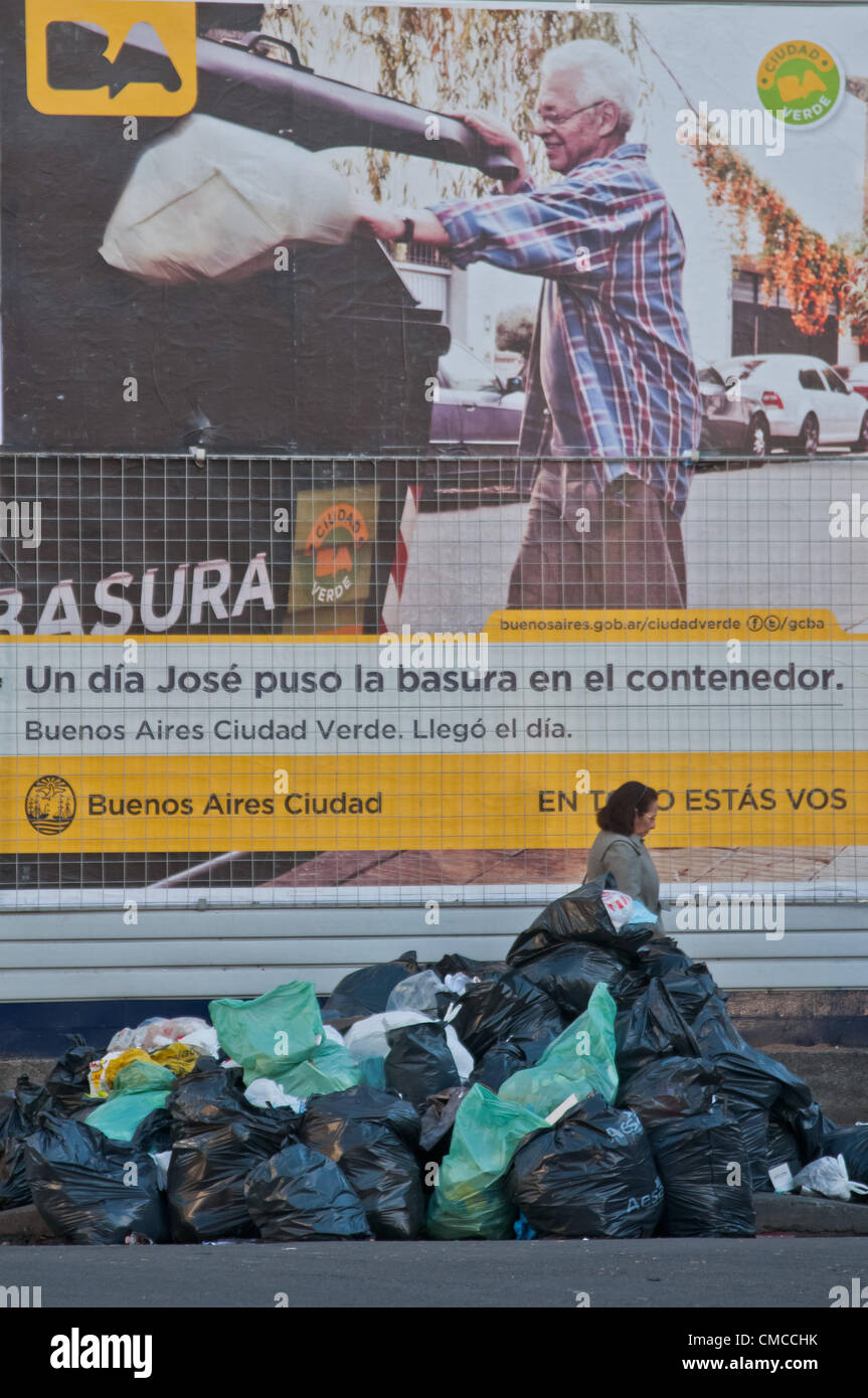 Luglio 17, 2012 - Buenos Aires, Buenos Aires, Argentina - una donna cammina davanti a un mucchio di rifiuti davanti a un poster che annuncia un nuovo garbage collection programma dal comune. Nel frattempo, uno sciopero da parte dei lavoratori del CEAMSE, la società che riceve ed elabora la spazzatura prodotta da Buenos Aires, ha lasciato la città senza la raccolta dei rifiuti per il secondo giorno. (Credito Immagine: © Patricio Murphy/ZUMAPRESS.com) Foto Stock
