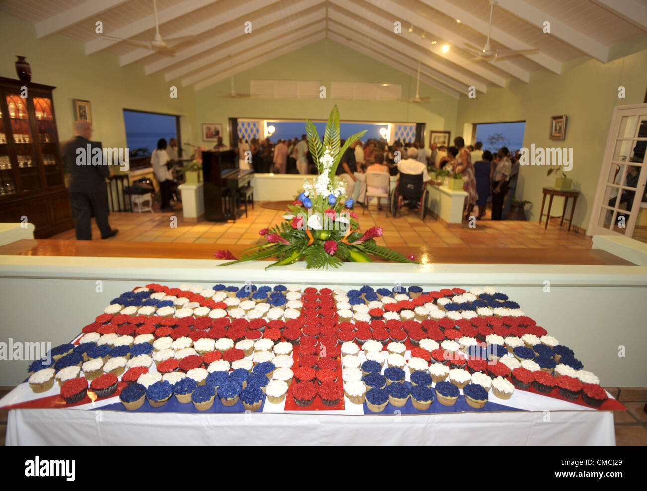 Giugno 22, 2012 - Montserrat, Regno Unito - tortine assumere la forma della bandiera britannica come regolatore di Adrian Davis di passeggiate in un partito al suo patrimonio privato nella celebrazione della regina di Inghilterra del Giubileo di diamante su Giugno 21, 2012. Nel 1995, il vulcano Sufriere violentemente eruttato, distruggendo la città di Plymouth e cambiare per sempre il paesaggio dell'isola di Montserrat. La Gran Bretagna ha promesso un aiuto nella ristrutturazione di una nuova città capitale che è protetto dal vulcano. (Credito Immagine: © Josh Edelson/ZUMAPRESS.com) Foto Stock