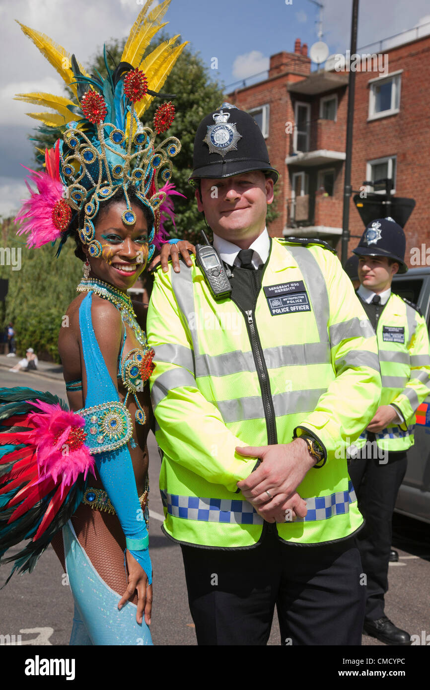 Hackney, Londra, Regno Unito. Sabato, 21 luglio 2012. Sfilata di Carnevale da Pitfield Street a Stoke Newington a uno Hackney Festival 2012. Il festival è tutto il giorno un borough ampia manifestazione che si svolge il sabato, 21 luglio 2012 ad accogliere la fiaccola olimpica sul suo primo giorno a Londra. La ballerina dalla London School of Samba in posa con un poliziotto. Foto Stock