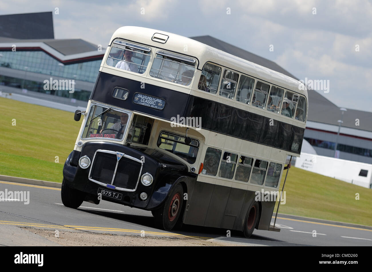 Il 21 luglio 2012, Silverstone, Regno Unito un classico double decker bus porta gli spettatori tra il paddock internazionale, visto in lontananza e il paddock nazionale a Silverstone Classic 2012 Foto Stock