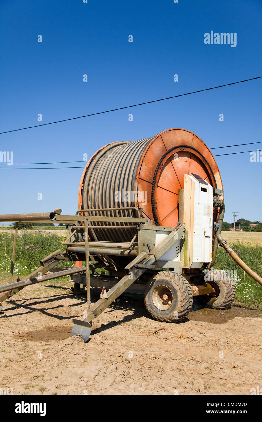 Bobina del tubo flessibile in corrispondenza del bordo di un campo (capezzagna) con cielo blu in Norfolk,UK,questo tubo aspo è alimentato con energia solare & ha la pompa acqua integrati che alimenta l'acqua all'irroratore nel campo. Foto Stock