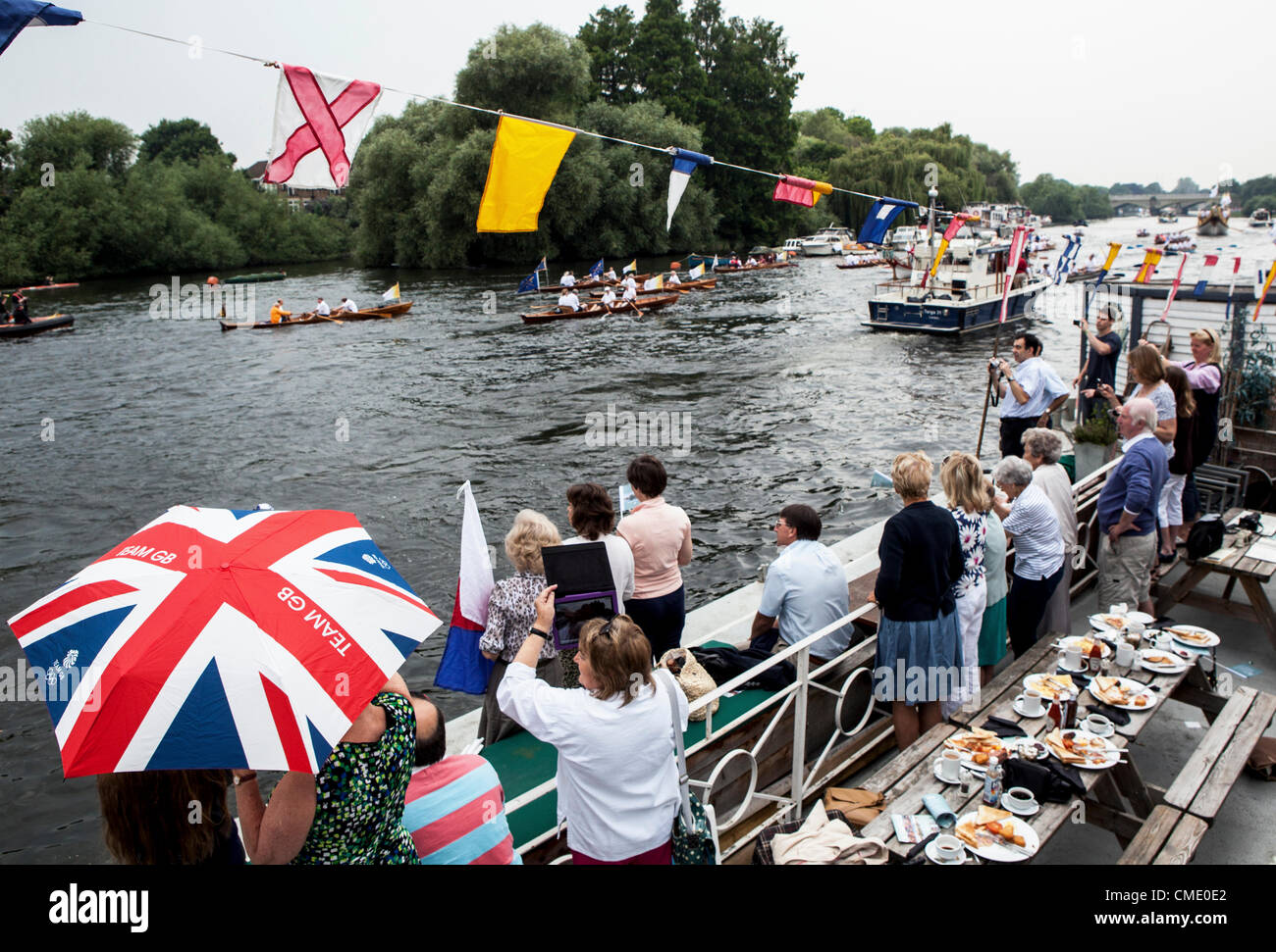 Il fiume Tamigi, Richmond Upon Thames, Greater London, Surrey, Regno Unito - Venerdì 27 Jaly 2012: La Torcia Olimpica ha preso al fiume di oggi. È stato portato su Vincenzo che ha portato una flottiglia di barche da Hampton Court Palace a Barnes. Persone rivestite le rive del fiume per godersi lo spettacolo. Foto Stock