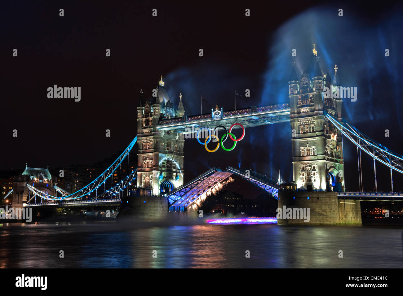 London, England, Regno Unito venerdì 27 luglio 2012 il Tower Bridge fuochi d'artificio illuminano il fiume Tamigi come la torcia olimpica visto qui come un sentiero di luce sotto il ponte, prende la tappa finale del viaggio verso lo Stadio Olimpico. Londra, ospite del trentesimo Giochi Olimpici preparato per la cerimonia di apertura con un fuoco d'artificio e display luminoso a Tower Bridge, City of London, England, Regno Unito Foto Stock
