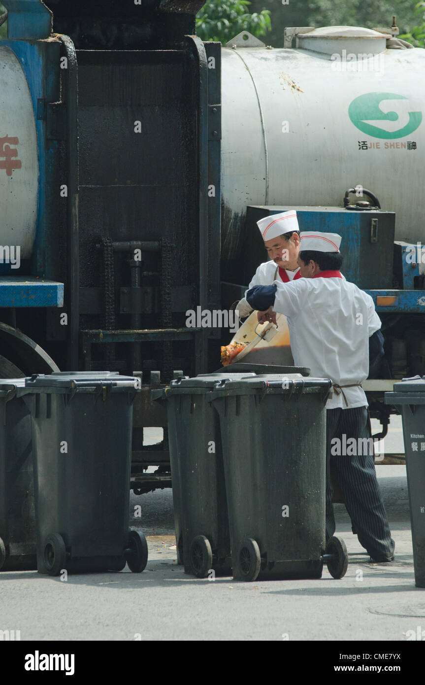 Un autocarro di riciclaggio ufficiale sta caricando i rifiuti alimentari di un ristorante. Secondo una recente dichiarazione del Consiglio di Stato, la sicurezza alimentare diventerà una misura del rendimento dei governi locali nelle loro valutazioni annuali. Recentemente sono emersi diversi scandali per la sicurezza alimentare, tra cui ristoranti che servono cibo cotto con "olio di grondaia": Olio da cucina riciclato dai rifiuti di cucina, grasso animale decomposto e organi provenienti dai macelli. Il ritrattamento dell'olio da cucina usato è spesso molto rudimentale; le tecniche includono la filtrazione, l'ebollizione, la raffinazione e la rimozione di alcuni adulteranti. © Olli Geibel Foto Stock