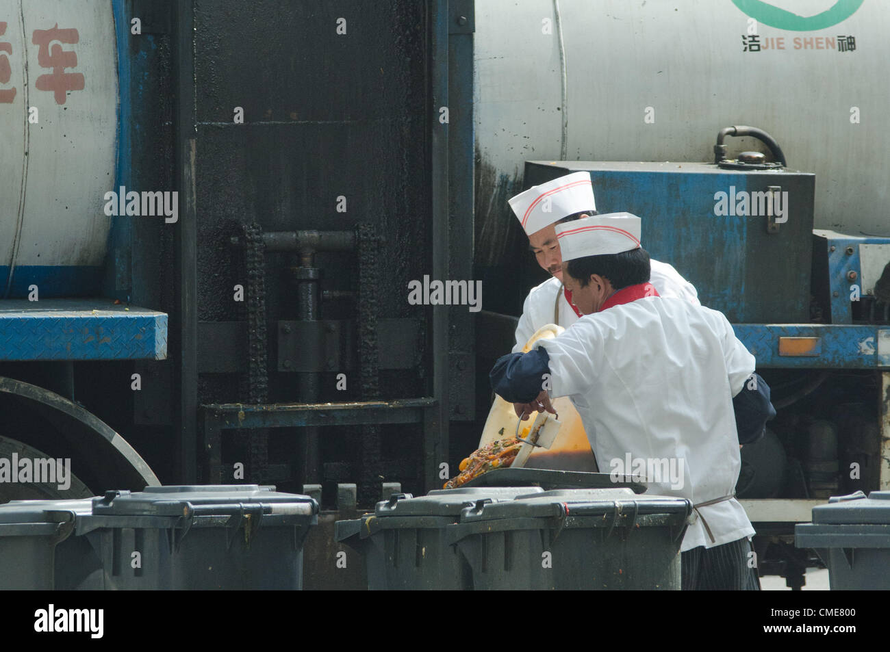 Un autocarro di riciclaggio ufficiale sta caricando i rifiuti alimentari di un ristorante. Secondo una recente dichiarazione del Consiglio di Stato, la sicurezza alimentare diventerà una misura del rendimento dei governi locali nelle loro valutazioni annuali. Recentemente sono emersi diversi scandali per la sicurezza alimentare, tra cui ristoranti che servono cibo cotto con "olio di grondaia": Olio da cucina riciclato dai rifiuti di cucina, grasso animale decomposto e organi provenienti dai macelli. Il ritrattamento dell'olio da cucina usato è spesso molto rudimentale; le tecniche includono la filtrazione, l'ebollizione, la raffinazione e la rimozione di alcuni adulteranti. © Olli Geibel Foto Stock