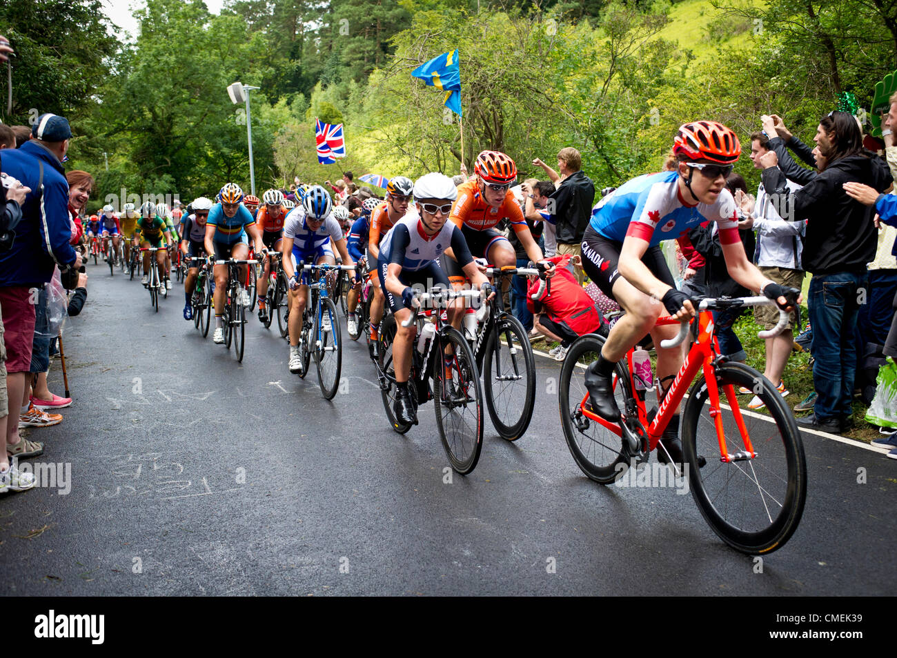 Il 29 luglio 2012. Olimpiadi di Londra per donna in bicicletta da corsa su strada. Il peloton al Box Hill nel Surrey. Emma Pooley del Team GB compiuto ogni sforzo per rimanere nella parte anteriore del poleton, accanto a Clara Hughes dal Canada che ha guidato il gruppo come essi accelerato fino al primo giro di Box Hill. Marianne Vos dai Paesi Bassi a cavallo sul retro di Emma Pooley durante la corsa su strada evento. Foto Stock