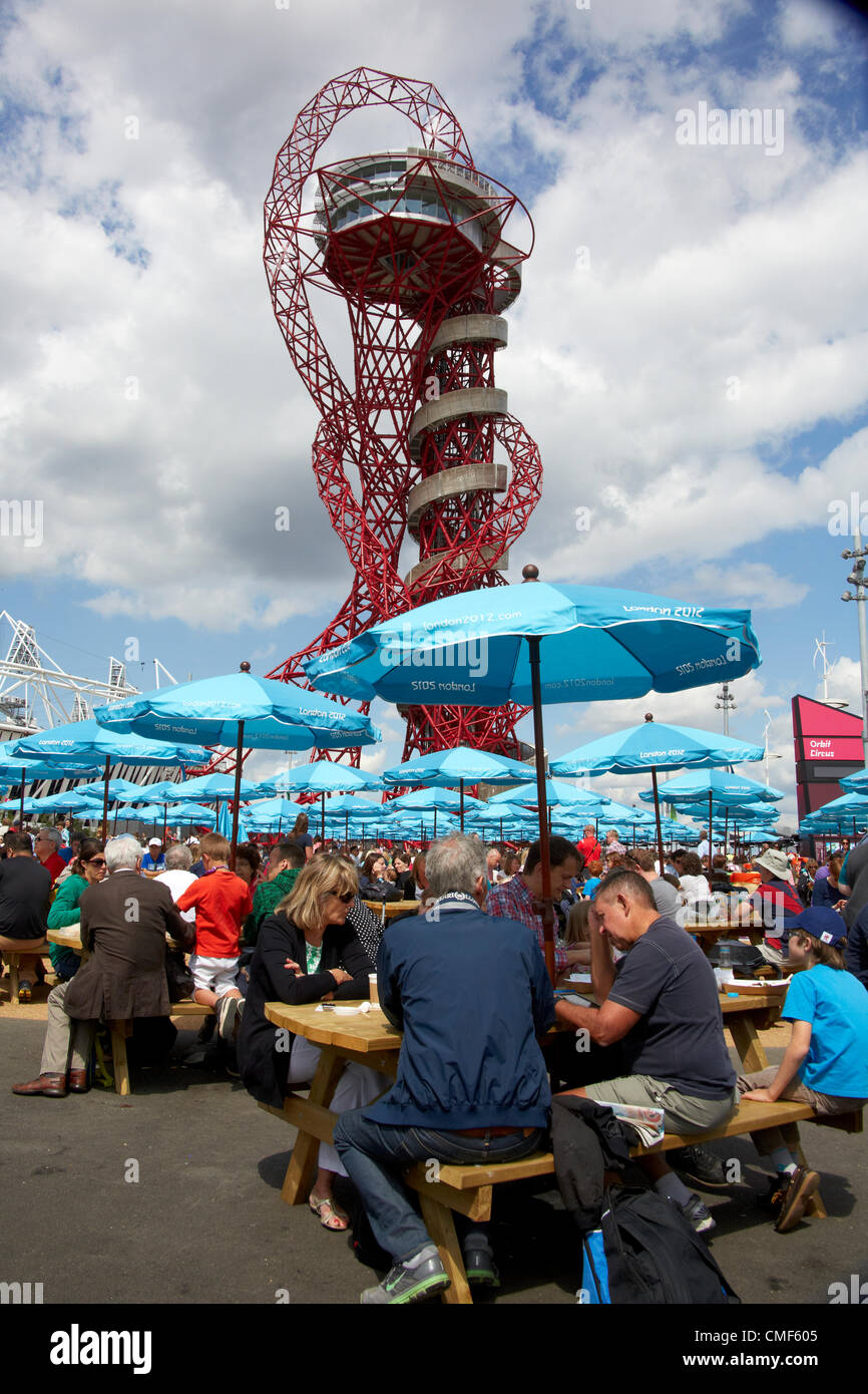 Persone mangiare nella luce del sole al di fuori orbita scultura torre progettata da Anish Kapoor in una giornata di sole al Parco Olimpico, Londra 2012 Giochi Olimpici sito, Stratford London E20, Regno Unito Foto Stock