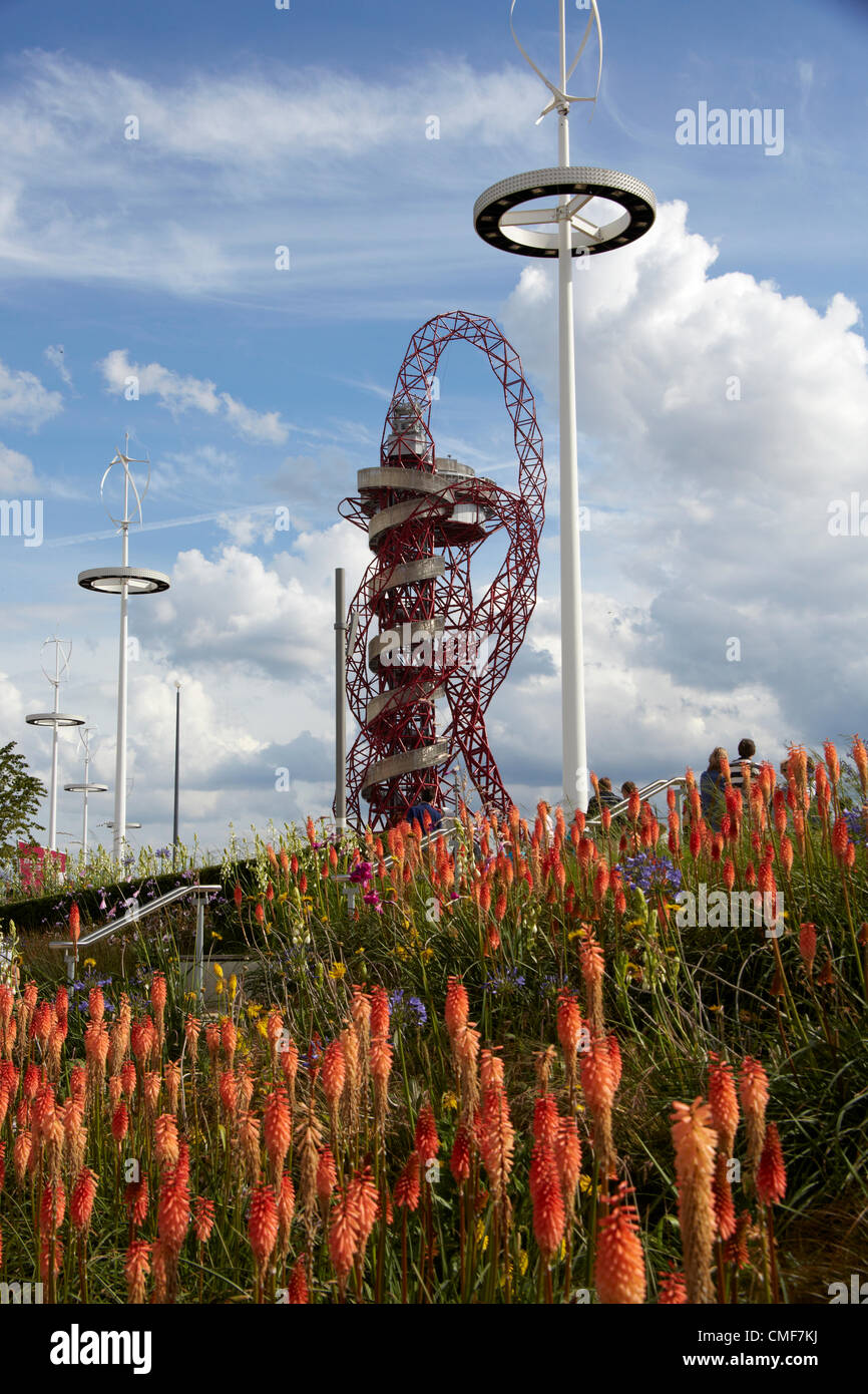 Orbita scultura torre progettata da Anish Kapoor e turbina eolica torre di illuminazione e il red hot poker fiori su una soleggiata giornata al Parco Olimpico, Londra 2012 Giochi Olimpici sito, Stratford London E20, Regno Unito Foto Stock