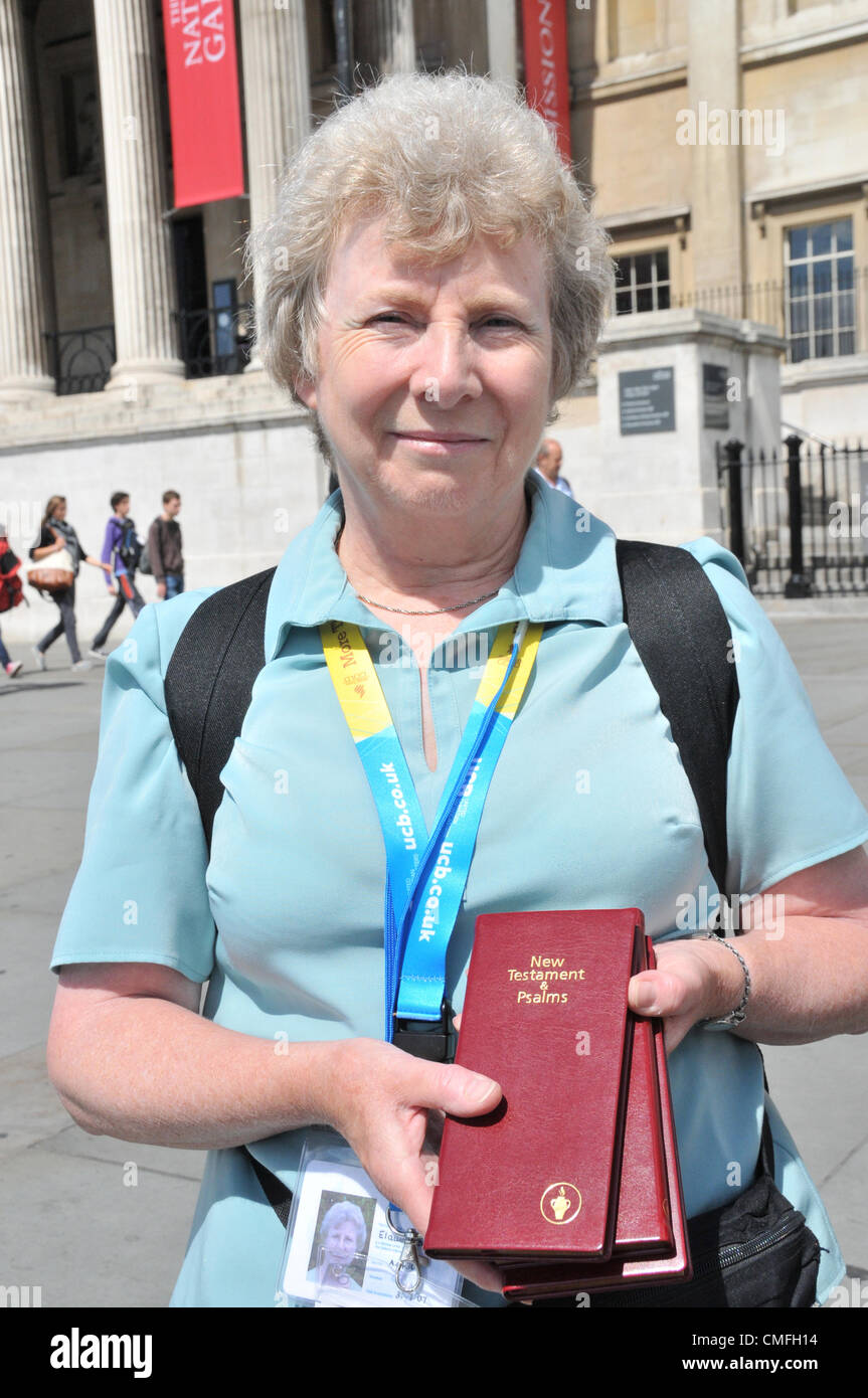 Il 3° agosto 2012. Trafalgar Square, Londra, Regno Unito. Il 3 agosto 2012. Una donna che indossa un "Olympic' distintivo di stile mani Gideons Nuovo Testamento in Trafalgar Square. I gruppi religiosi sono nel centro di Londra, molti utilizzando le Olimpiadi di temi in alcune delle loro attività per attrarre nuovi credenti. Foto Stock