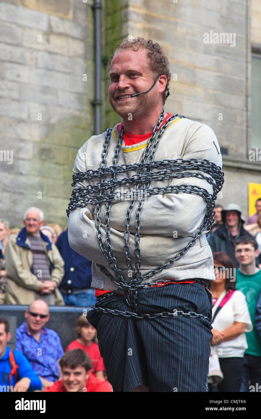 Il 18 agosto 2012. Byron Bertram, da Vancouver, Canada esecuzione in Hunter Square, Edimburgo al Edinburgh Fringe Festival. Byron Bertram è stato stava compiendo un atto di escapology utilizzando catene e una camicia di forza in corrispondenza di una sede esterna. Foto Stock