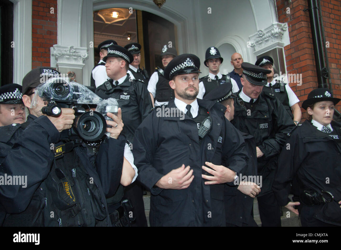 19 agosto 2012. Londra REGNO UNITO. Gli ufficiali di polizia e forze di polizia fotografi stand al di fuori dell'Ecuador ambasciata del giorno Wikileaks fondatore risolve una folla di tifosi dal balcone dell'Ecuador ambasciata. Signor Assange fa la sua prima dichiarazione pubblica fin dal suo ingresso nell'ambasciata Ecuador il 19 giugno 2012 Foto Stock