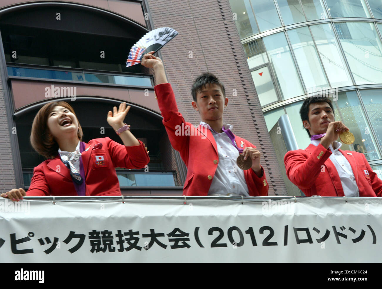 Agosto 20, 2012, Tokyo, Giappone - atleti olimpionici wave dalla cima di open top double-decker bus come hanno sempre primo homecoming parade giù per la strada principale di Tokyo il quartiere dello shopping di Ginza Lunedì, Agosto 20, 2012, per onorare i loro successi al 2012 Olimpiadi di estate a Londra. Settanta-sei premiati con medaglie gli atleti sfilavano lungo il boulevard foderato con centinaia di migliaia di tifo, sbandieratori di ben wishers. Essi sono, da sinistra: Ai Fukuhara di tennis da tavolo e Satoshi Shimizu e Ryota Murata, entrambi della boxe. (Foto di Natsuki Sakai/AFLO) Foto Stock