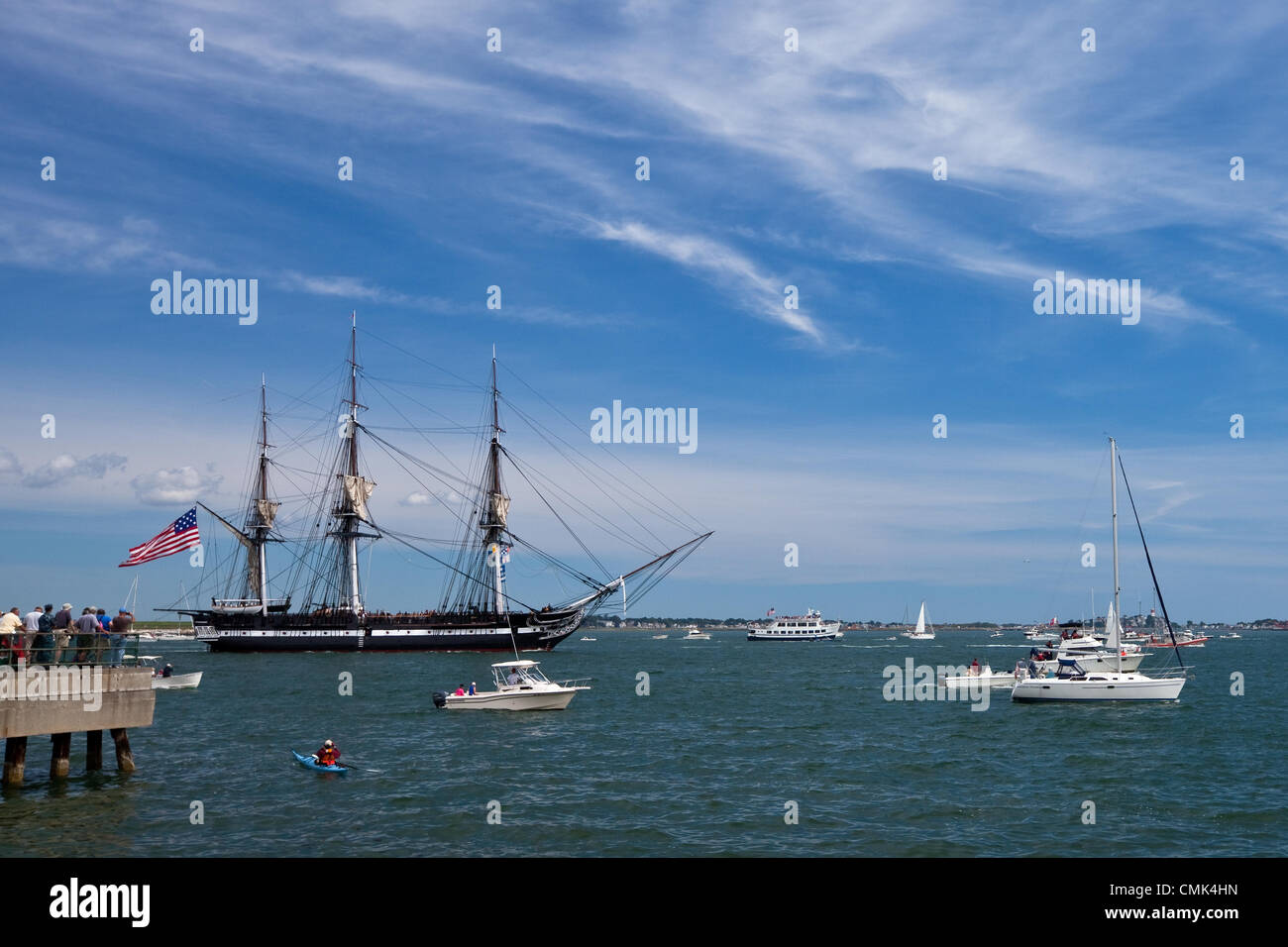 Gli spettatori e imbarcazioni da diporto si riuniscono per guardare la USS Constitution testa fuori per una vela commemorativa in Boston Harbor, segnando il giorno ha sconfitto la fregata britannica HMS guerriere e si è guadagnato il soprannome di 'Old Ironsides' durante la guerra del 1812. Foto Stock