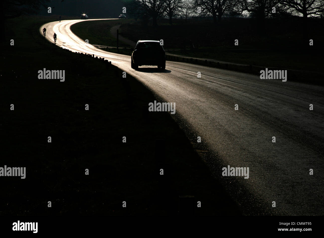Le automobili e i ciclisti viaggiano attraverso il parco di Richmond a segatori Hill, Richmond, London, Regno Unito Foto Stock