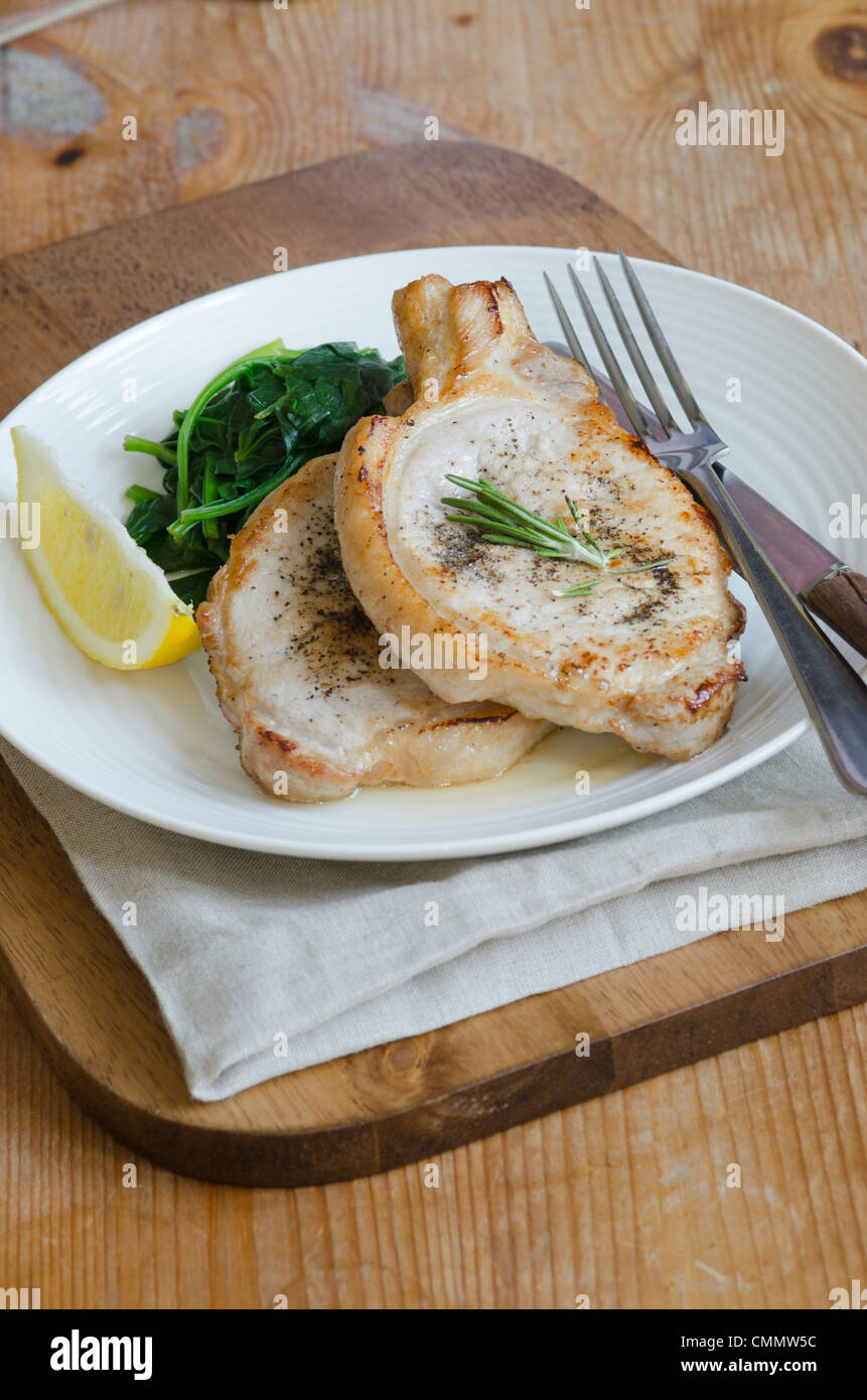 La carne di maiale con spinaci appassito su una piastra Foto Stock