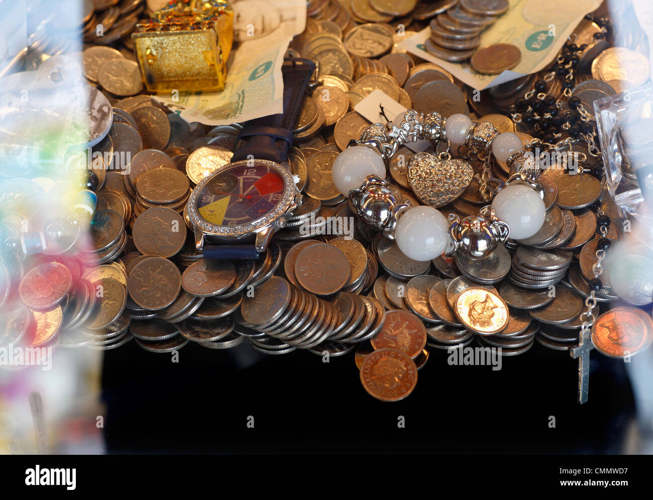 Monete e ninnoli in un penny fontana gioco a una fiera del divertimento. Foto Stock