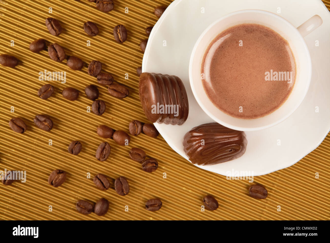 Al di sopra di vista della tazza di caffè con pralina e grani nelle vicinanze Foto Stock