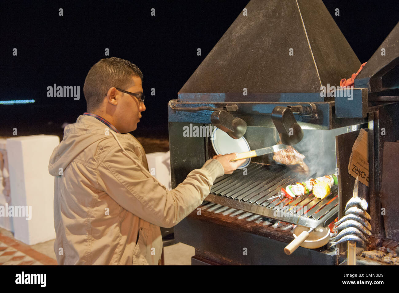 Chef di cottura degli alimenti su Benalmadena fronte mare all'aperto su un barbecue su carbone caldo Foto Stock