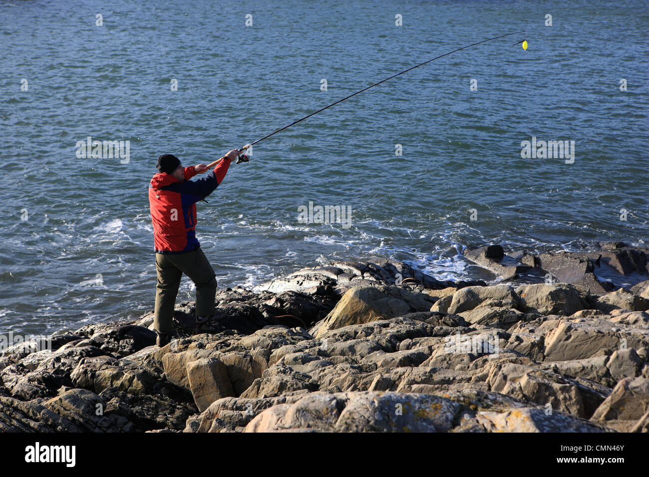 L'uomo la colata di una canna da pesca a bordo delle acque Foto Stock