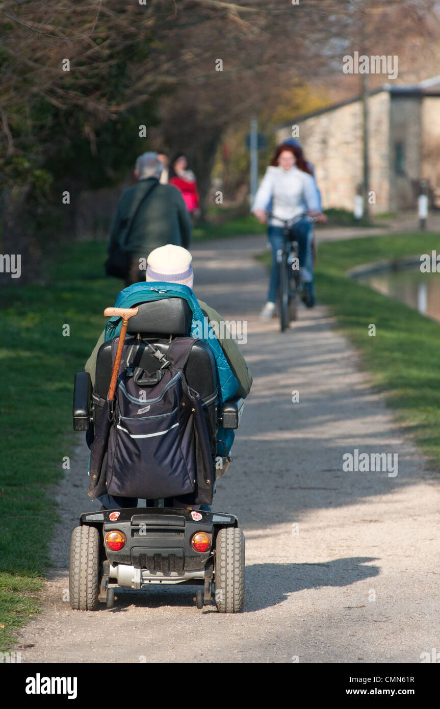 Old Lady in sella al suo scooter di mobilità sul sentiero lungo il fiume Cam in Cambridgeshire, Inghilterra. Foto Stock