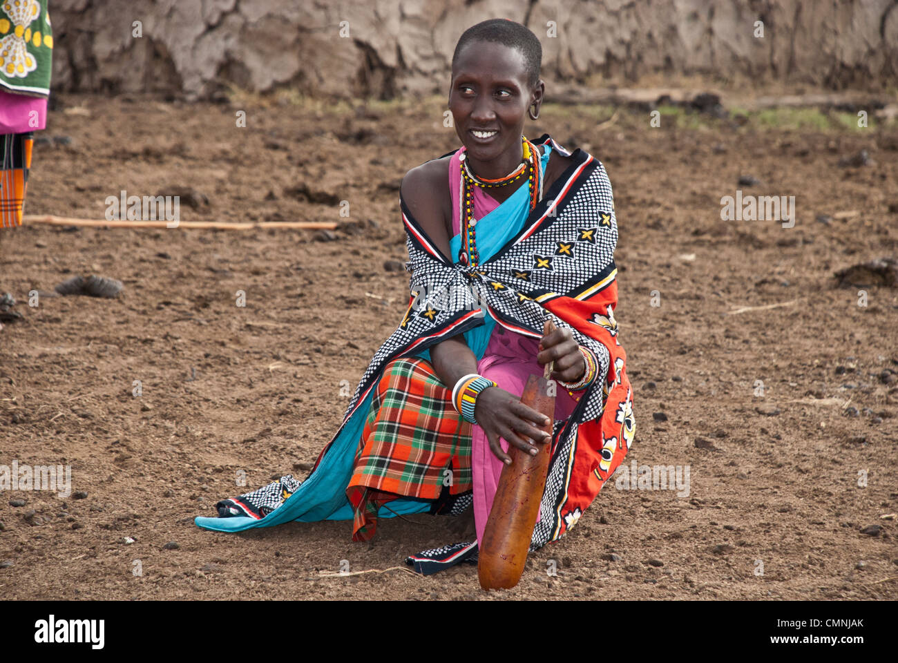 Masai donna, indossando variopinti abiti tradizionali, agitazione di una vacca di sangue in una zucca per rimuovere i grumi prima di essere consumato. Foto Stock