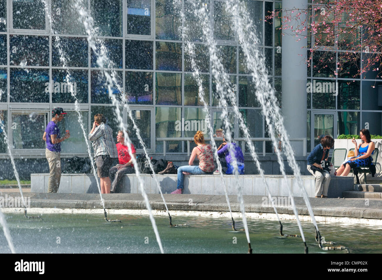 Le persone che si godono il primo sole di primavera su una calda giornata nel parco cittadino con fontana a Gand, Belgio Foto Stock