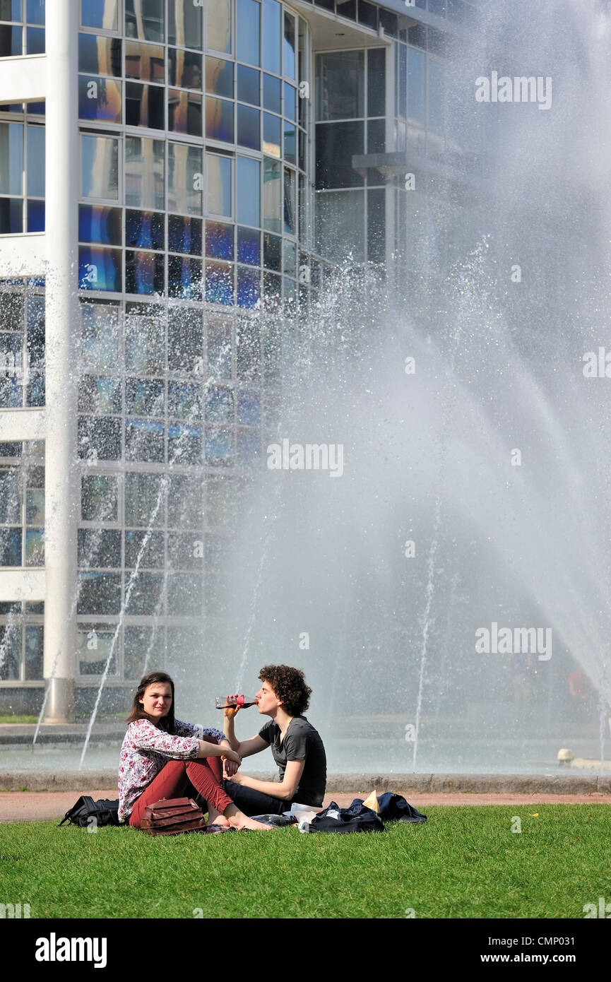 Coppia di ragazzi godendo il primo sole di primavera su una calda giornata nel parco cittadino con fontana a Gand, Belgio Foto Stock