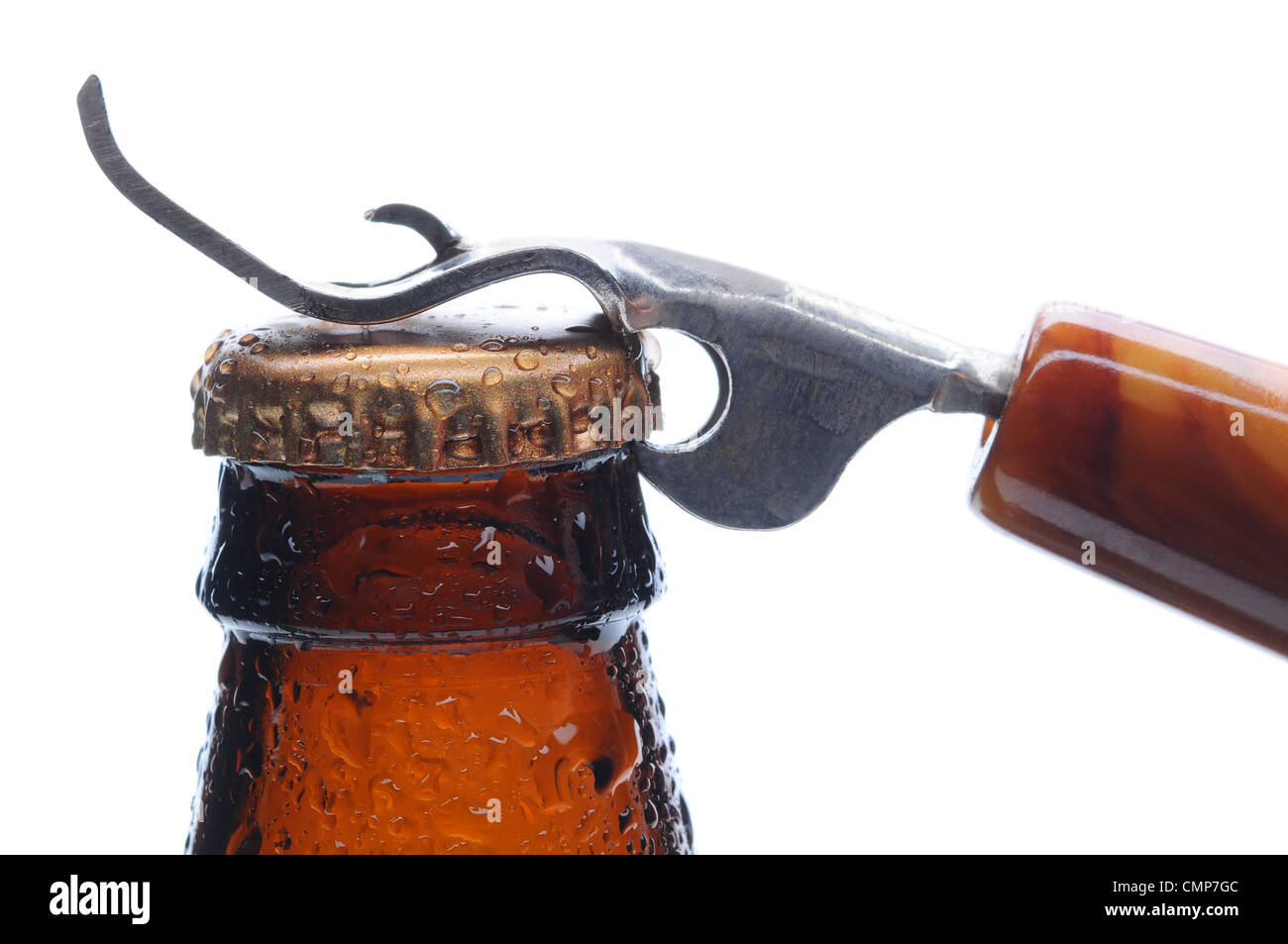 Ripresa macro di un marrone bottiglia di birra con un apritoio pronto a sollevare il tappo di bottiglia. Foto Stock