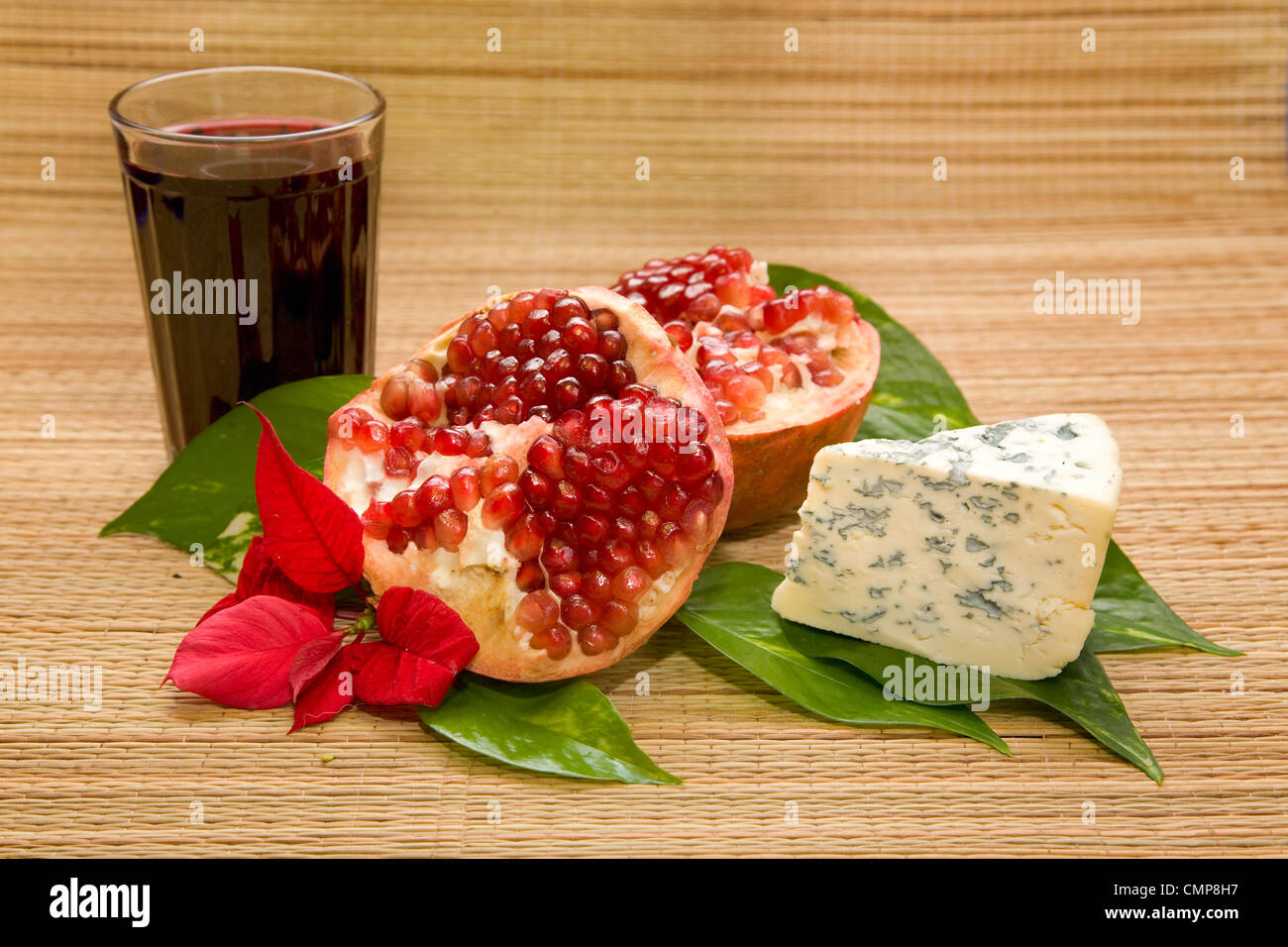 Formaggio con stampo e melograno con un bicchiere di vino sul materassino Foto Stock