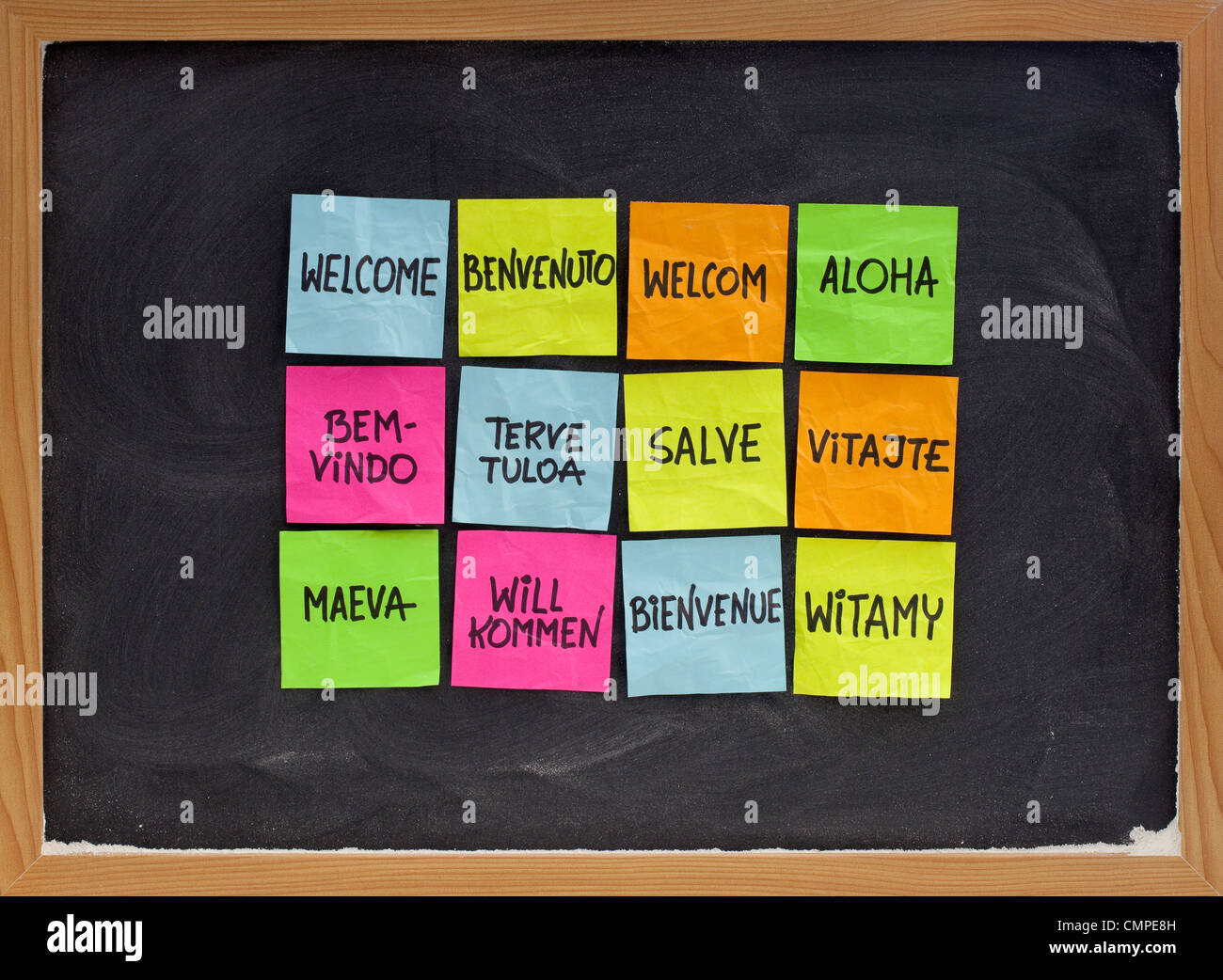 Benvenuti in una dozzina di lingue - array di coloratissimi sticky notes sulla lavagna con gesso bianco texture Foto Stock