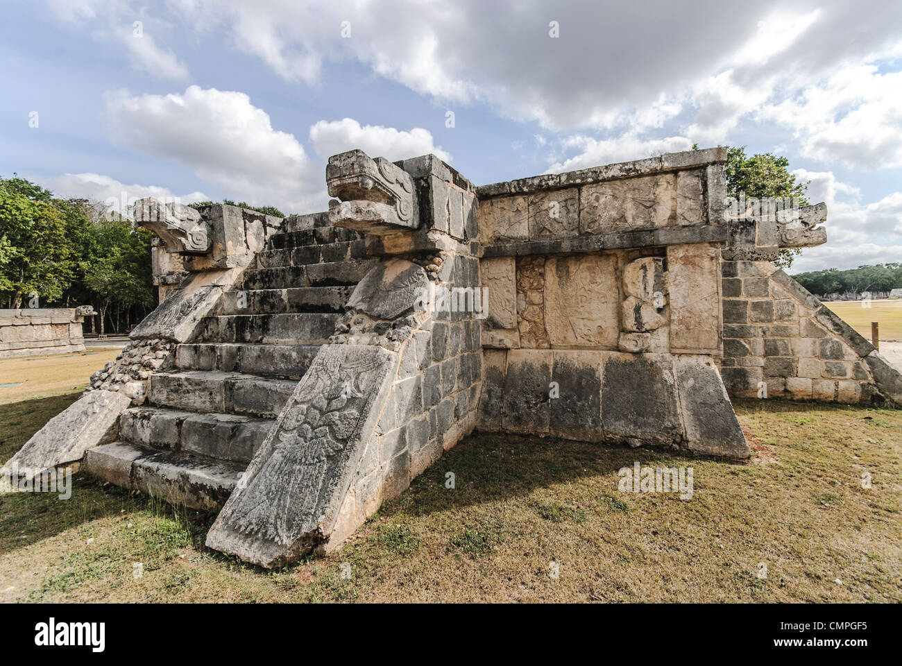 Chichen Itza Venus Platform Jaguar Head Sculptures Messico // CHICHEN ITZA, Messico - la piattaforma Venere, una struttura cerimoniale compatta nell'antica città Maya di Chichen Itza, presenta sculture distintive della testa di jaguar che fiancheggiano la sua scalinata. La piattaforma, dedicata al pianeta Venere, dimostra la sofisticata comprensione dell'astronomia dei Maya e la sua integrazione nell'architettura religiosa. Questa struttura si trova vicino alla piazza centrale del complesso archeologico, che fa parte del nucleo cerimoniale della città. Foto Stock