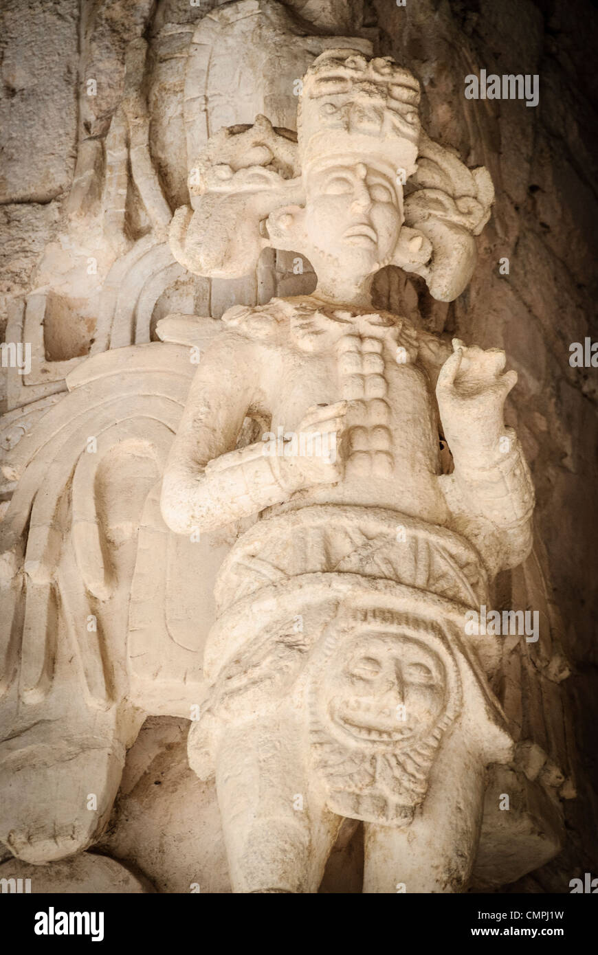 EK Balam Maya stucco Figure Mexico // EKBALAM, Mexico — figure in stucco elaborate scolpite con elementi piumati simili ad ali affiancano l'ingresso a bocca del mostro all'Acropoli di Ekʼ Balam (noto anche come Ek Balam). Mentre la loro caratterizzazione e il loro significato sono dibattuti, questi rilievi scultorei a grandezza naturale, creati intorno al 770-840 d.C. durante il tardo periodo classico, possono rappresentare esseri soprannaturali o antenati deificati associati alla tomba del sovrano Ukit Kan le'k Tok'. Le figure mostrano intricati dettagli del costume, tra cui cinture cerimoniali, copricapi e caratteristici zaini piumati che di Foto Stock