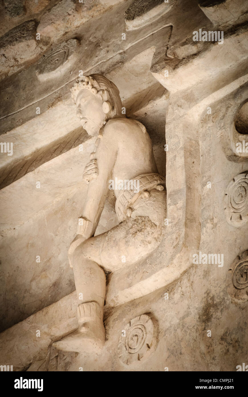 EK Balam Acropolis tardo classico Maya stucco Figura Messico // EKBALAM, Messico - figure in stucco elaborate scolpite con elementi piumati simili ad ali fiancheggiano l'ingresso a bocca del mostro all'Acropoli di Ekʼ Balam (noto anche come Ek Balam). Mentre la loro caratterizzazione e il loro significato sono dibattuti, questi rilievi scultorei a grandezza naturale, creati intorno al 770-840 d.C. durante il tardo periodo classico, possono rappresentare esseri soprannaturali o antenati deificati associati alla tomba del sovrano Ukit Kan le'k Tok'. Le figure mostrano intricati dettagli del costume, tra cui cinture cerimoniali, copricapi e prodezza distintiva Foto Stock