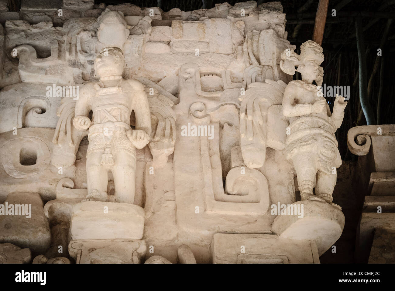EK Balam Acropolis Stucco figure Messico // EKBALAM, Messico — figure in stucco elaborate scolpite con elementi piumati simili ad ali fiancheggiano l'ingresso a bocca del mostro all'Acropoli di Ekʼ Balam (noto anche come Ek Balam). Mentre la loro caratterizzazione e il loro significato sono dibattuti, questi rilievi scultorei a grandezza naturale, creati intorno al 770-840 d.C. durante il tardo periodo classico, possono rappresentare esseri soprannaturali o antenati deificati associati alla tomba del sovrano Ukit Kan le'k Tok'. Le figure mostrano intricati dettagli del costume, tra cui cinture cerimoniali, copricapi e caratteristici zaini in piuma Foto Stock