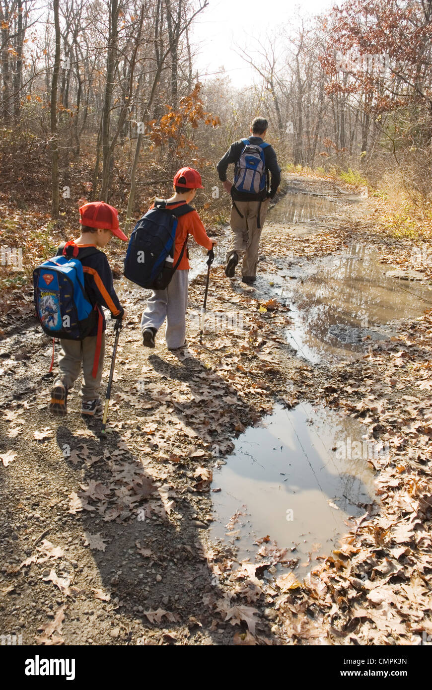 Due ragazzi piccoli e il loro padre a piedi nei boschi Foto Stock