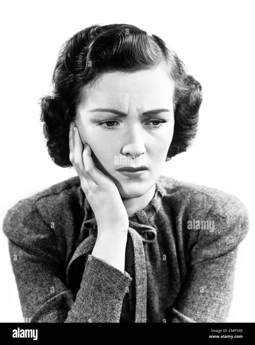 1940s preoccupato donna accigliata tenendo la mano alla guancia Foto Stock