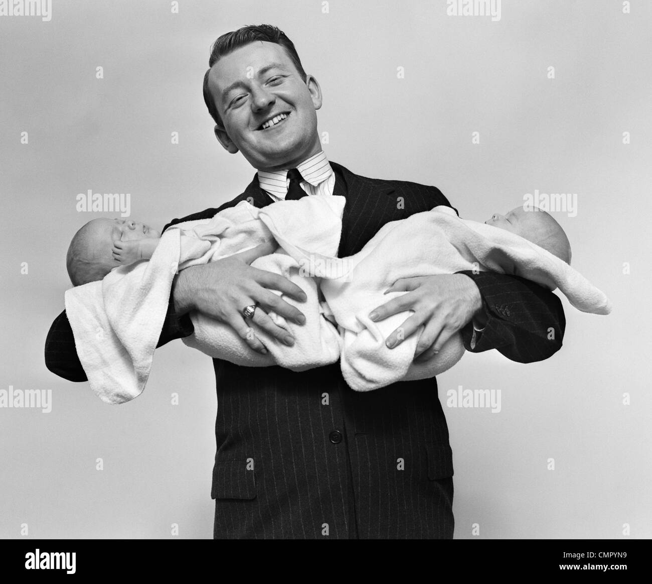 1930s orgoglioso padre sorridente orgogliosamente gemello di neonati Foto Stock