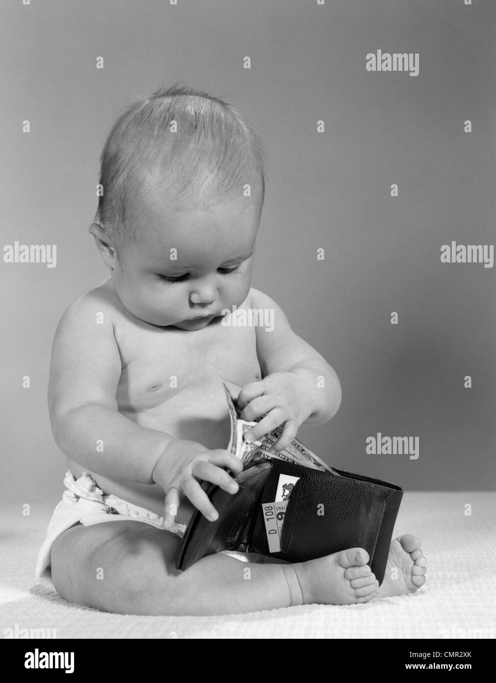 Anni sessanta BABY SITTING indossa pannolino tenendo la carta moneta AL DI FUORI DEL PORTAFOGLIO Foto Stock