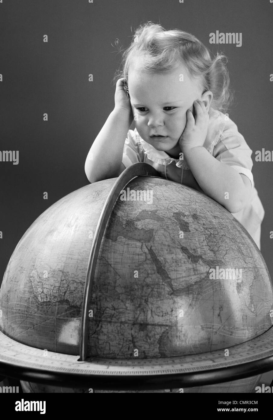 1940s BABY GUARDANDO appoggiata sul globo terrestre DI MESSA A TERRA Foto Stock