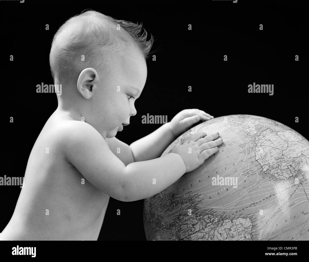 1940s bambino con le mani sul globo terrestre GUARDANDO LA MESSA A TERRA Foto Stock