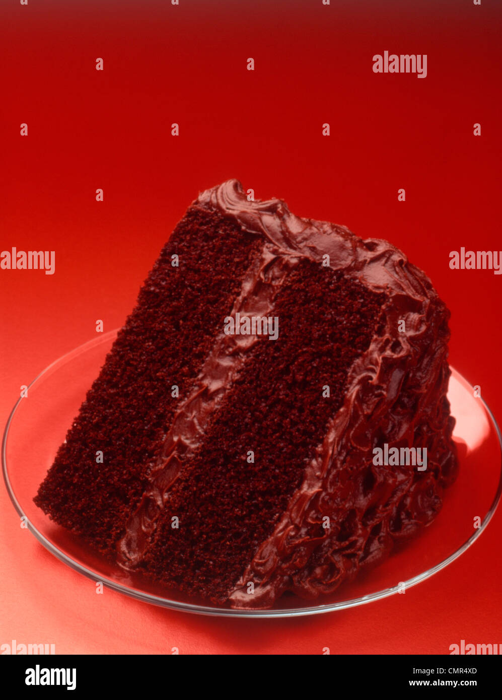 Anni sessanta fetta di due strati di torta al cioccolato sul piatto di vetro sfondo rosso Foto Stock