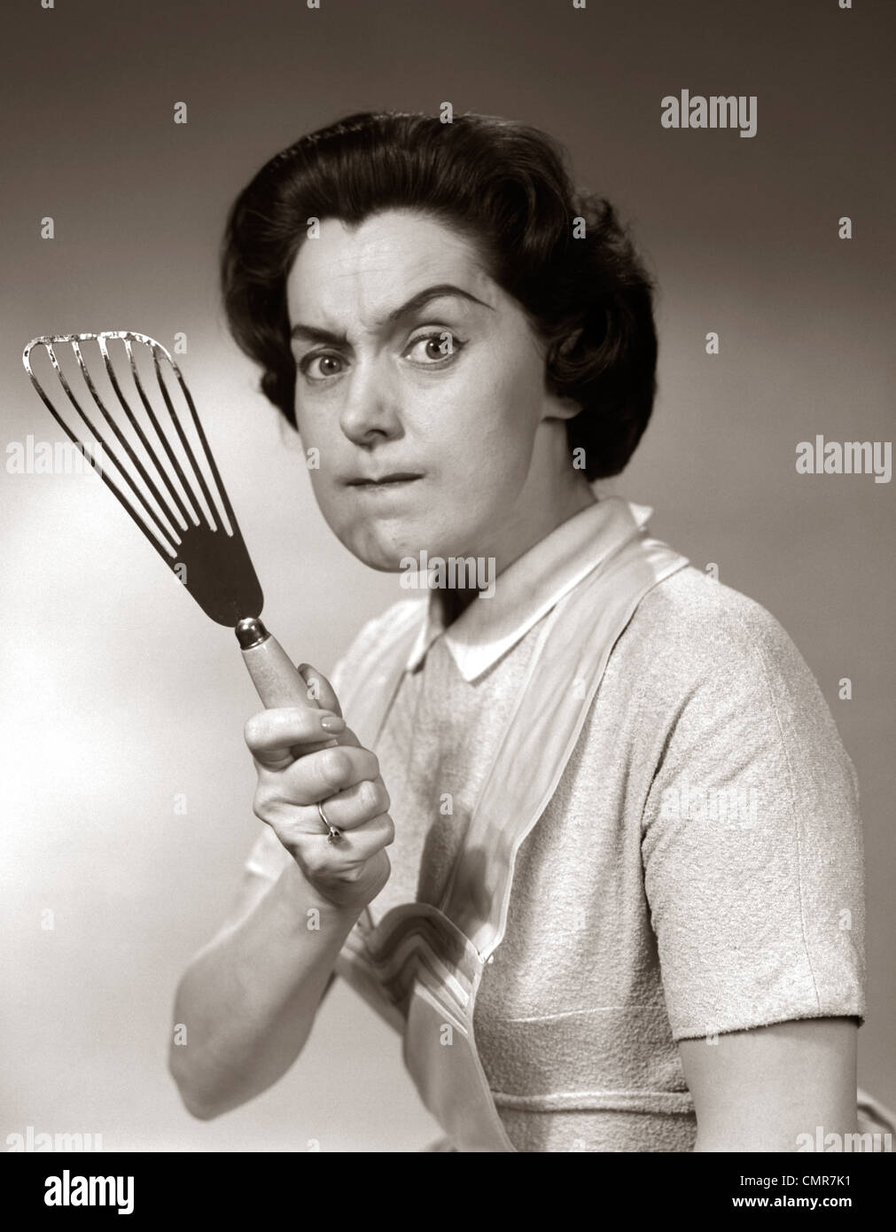 1950s-60s ritratto di Angry casalinga brandendo la spatola in telecamera Foto Stock