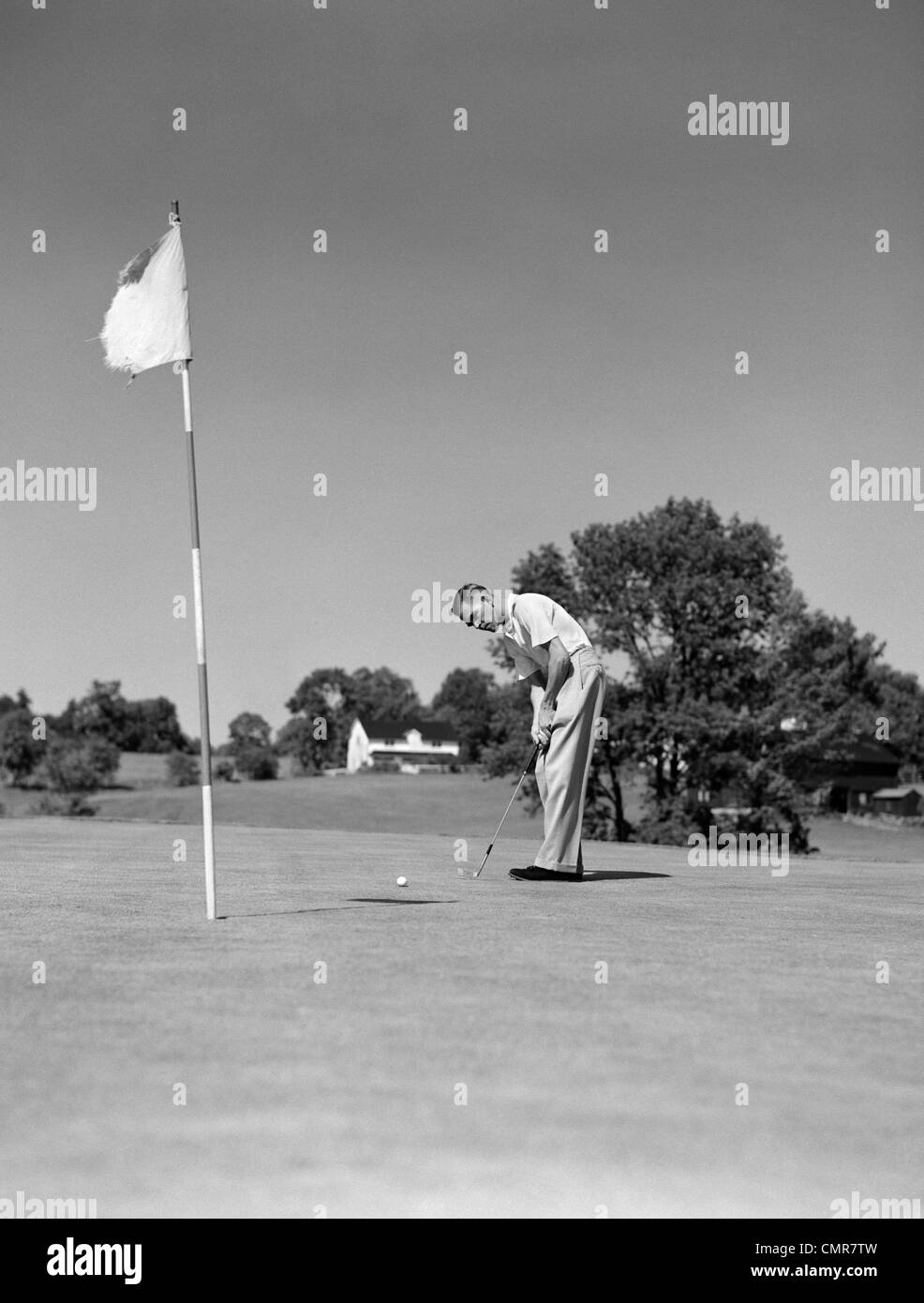 Anni Cinquanta uomo giocando a golf putting pallina da golf sul green a bandiera e la tazza per esterno Foto Stock